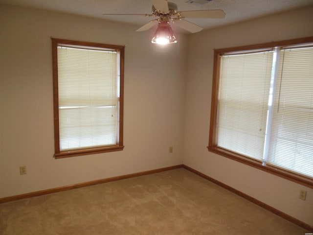 empty room with baseboards, visible vents, a ceiling fan, and light colored carpet