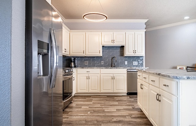 kitchen featuring stainless steel appliances, crown molding, light wood-type flooring, pendant lighting, and backsplash