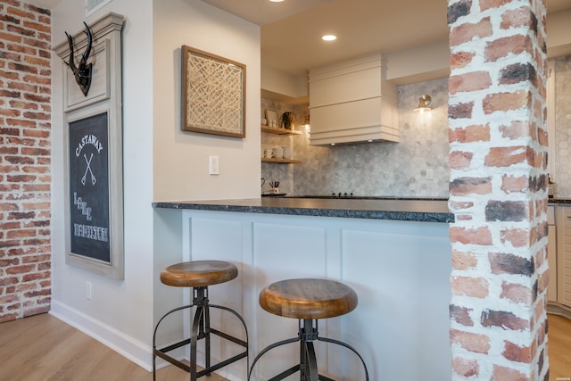 101 Long Island Dr Unit 303, Hot Springs, AR 71913 - kitchen with a kitchen breakfast bar, backsplash, dark countertops, brick wall, and wood finished floors