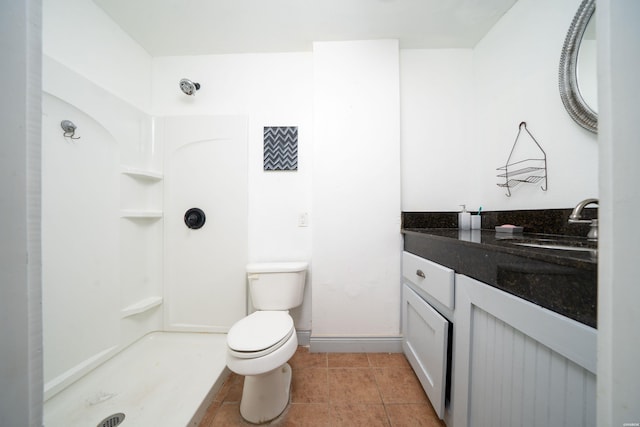 bathroom with vanity, baseboards, a shower, tile patterned floors, and toilet