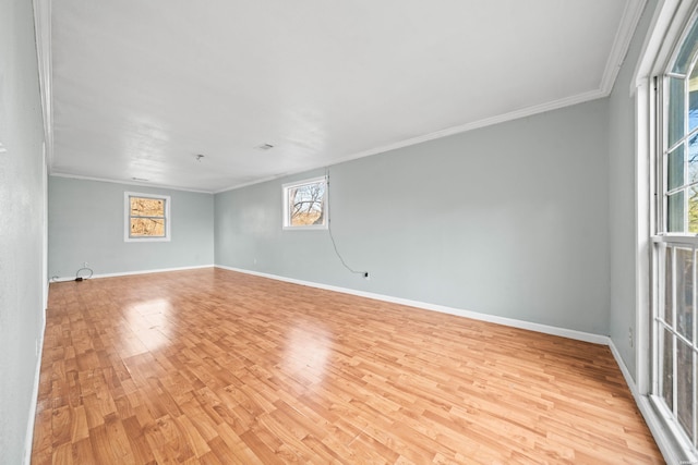 empty room featuring baseboards, crown molding, and light wood finished floors