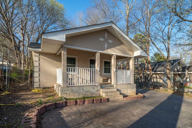 view of front of house with fence, covered porch, and stucco siding