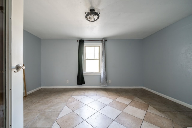 spare room with light tile patterned floors and baseboards