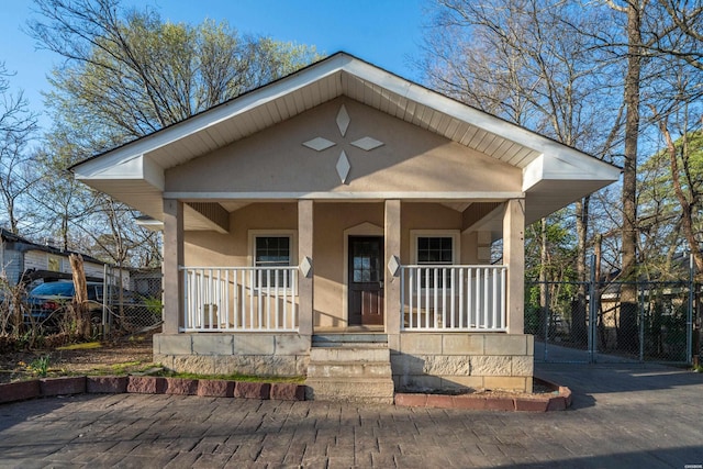 view of front of house featuring a gate, fence, covered porch, and stucco siding