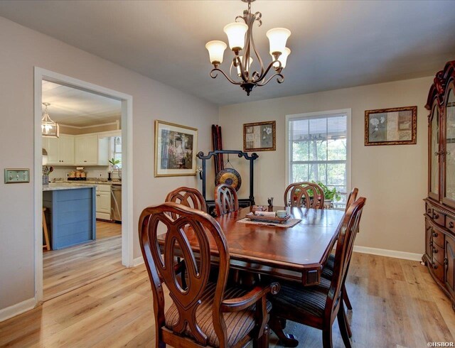 dining area featuring a notable chandelier, light wood-style flooring, and baseboards