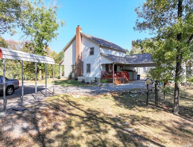 view of side of property with a carport, a chimney, and driveway