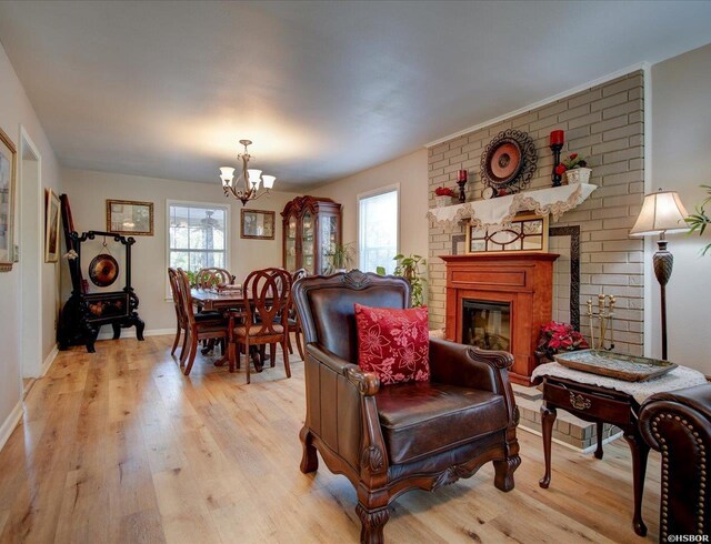 interior space featuring light wood-type flooring, a healthy amount of sunlight, a notable chandelier, and a fireplace