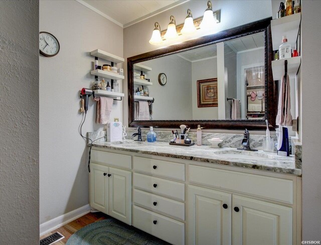 bathroom featuring double vanity, visible vents, a sink, and ornamental molding