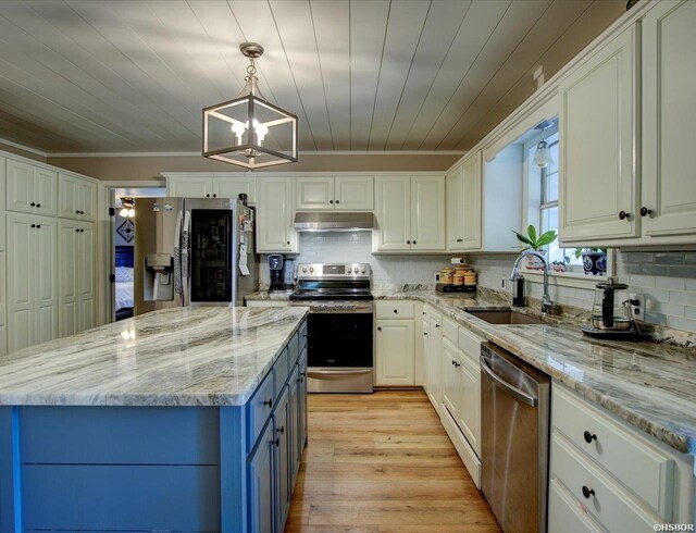 kitchen featuring white cabinets, stainless steel appliances, decorative light fixtures, and under cabinet range hood