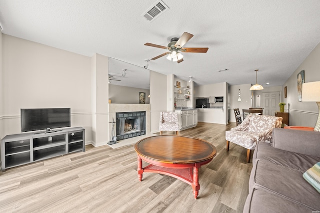 5371 Central Ave Unit 5L, Hot Springs, AR 71913 - living room featuring a ceiling fan, wood finished floors, a tiled fireplace, and a textured ceiling