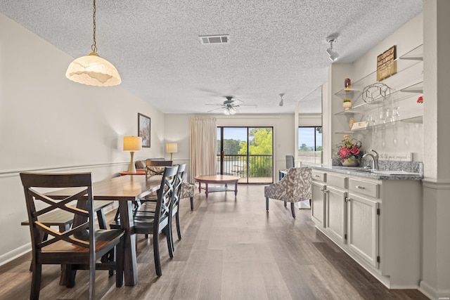 5371 Central Ave Unit 5L, Hot Springs, AR 71913 - dining room featuring a textured ceiling, dark wood-type flooring, bar with sink, and ceiling fan