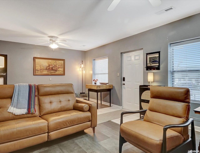 living room featuring ceiling fan, visible vents, and baseboards