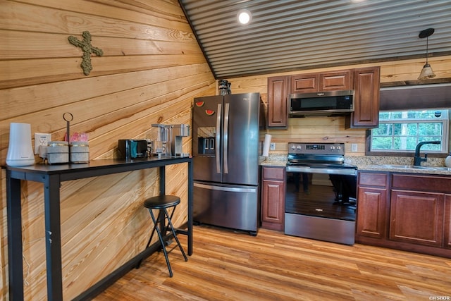 152 Anderson Loop, Amity, AR 71921 - kitchen with stainless steel appliances, wood walls, light wood-style flooring, pendant lighting, and light stone countertops