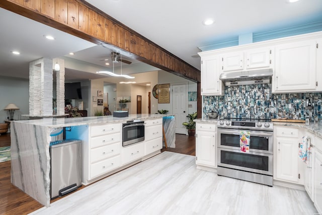 kitchen featuring decorative backsplash, double oven range, light stone countertops, white cabinets, and under cabinet range hood