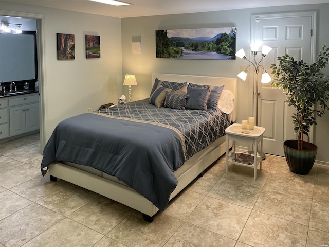 bedroom with light tile patterned floors, a sink, and ensuite bath