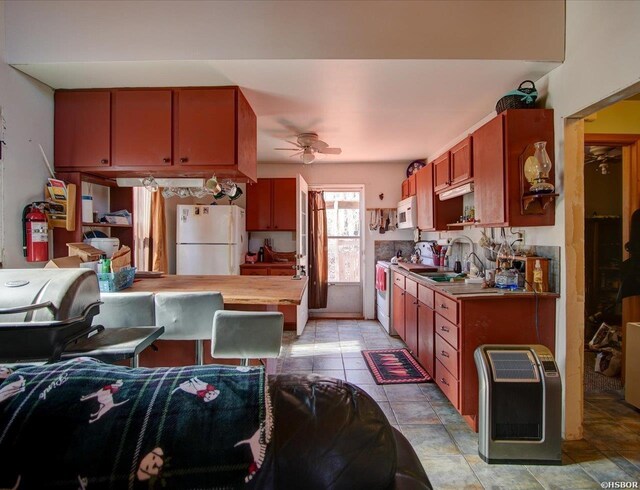 kitchen with white appliances, a ceiling fan, heating unit, light countertops, and a sink