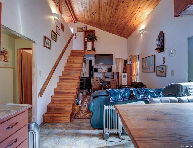 living area featuring high vaulted ceiling, wooden ceiling, and stairs