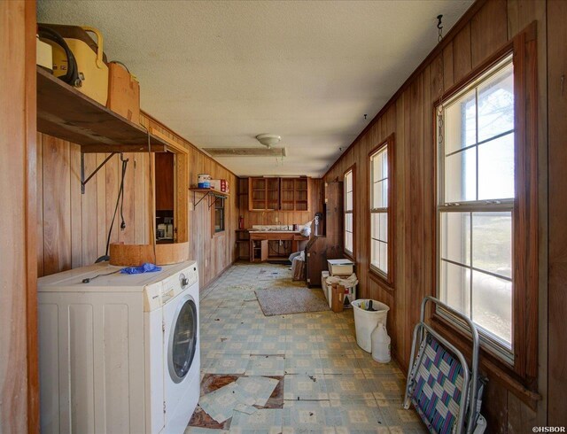 washroom featuring a textured ceiling, laundry area, washer / clothes dryer, and wooden walls