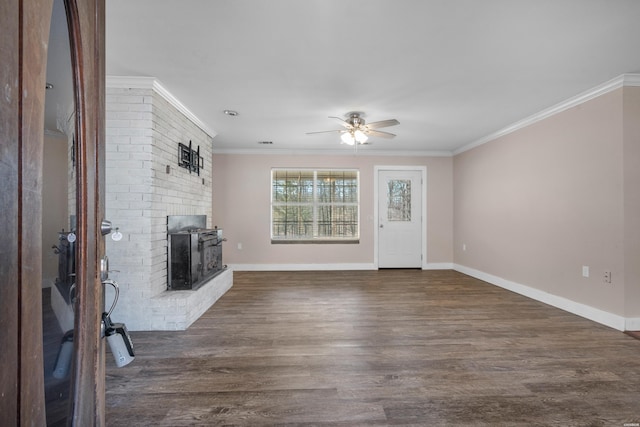 unfurnished living room with dark wood-type flooring, a brick fireplace, baseboards, and ornamental molding