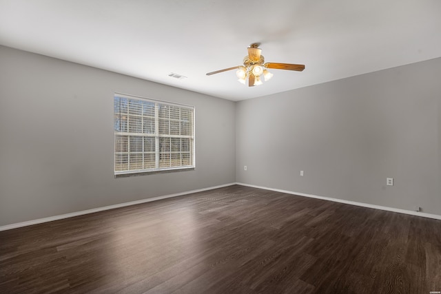 spare room with dark wood finished floors, baseboards, visible vents, and a ceiling fan