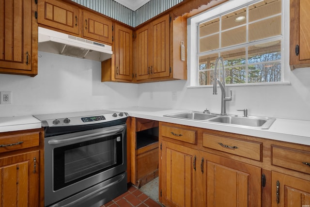 kitchen featuring brown cabinets, under cabinet range hood, a sink, stainless steel range with electric cooktop, and light countertops