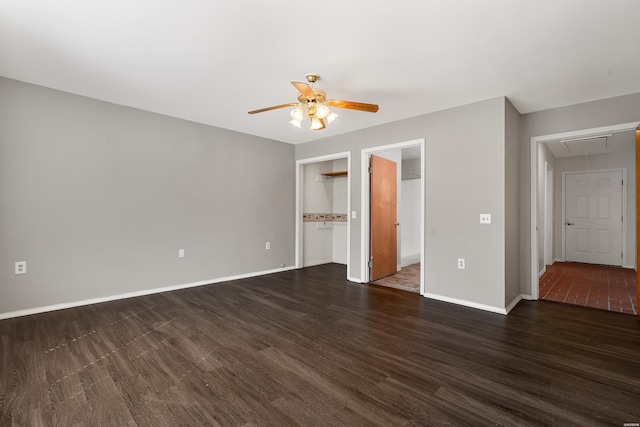 unfurnished bedroom featuring dark wood-type flooring, a closet, baseboards, attic access, and ceiling fan