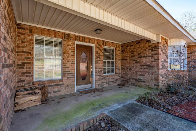 view of exterior entry featuring brick siding and board and batten siding