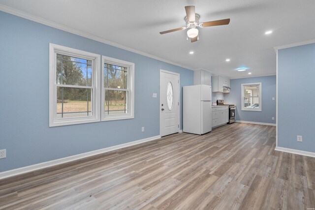 unfurnished living room featuring recessed lighting, light wood-style flooring, ornamental molding, a ceiling fan, and baseboards