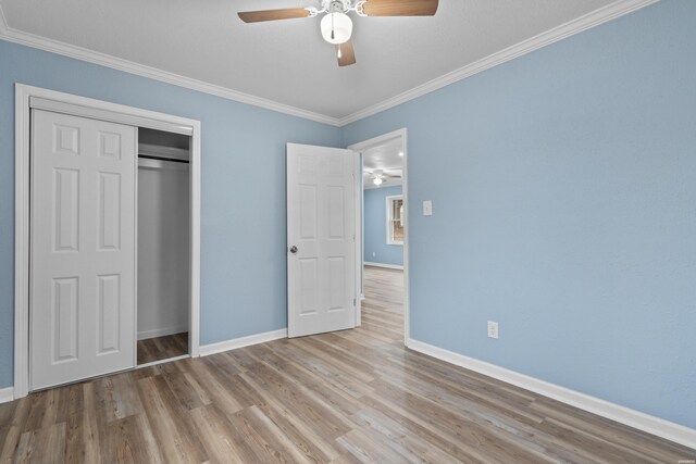 unfurnished bedroom with ceiling fan, baseboards, ornamental molding, a closet, and light wood finished floors