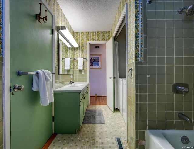 full bath with visible vents, a textured ceiling, vanity,  shower combination, and wallpapered walls