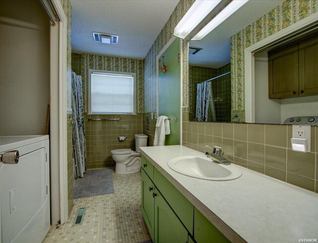 full bath featuring a textured ceiling, visible vents, tile walls, washer / dryer, and wallpapered walls