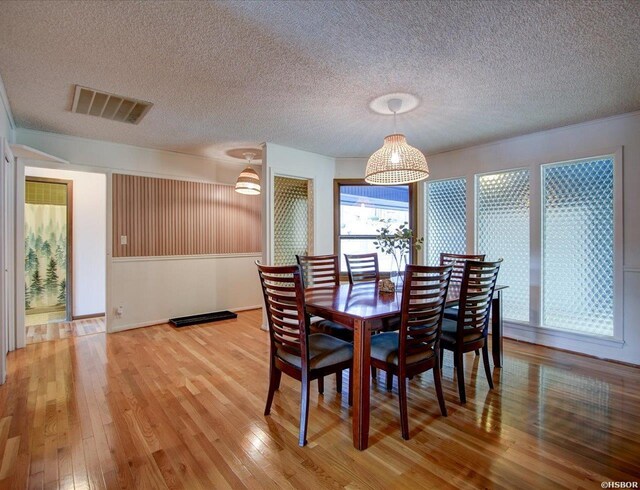 dining room featuring a textured ceiling, visible vents, and wood finished floors