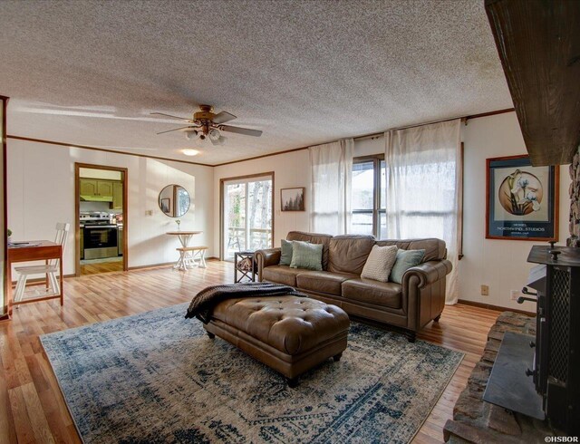 living area with crown molding, ceiling fan, a textured ceiling, wood finished floors, and baseboards