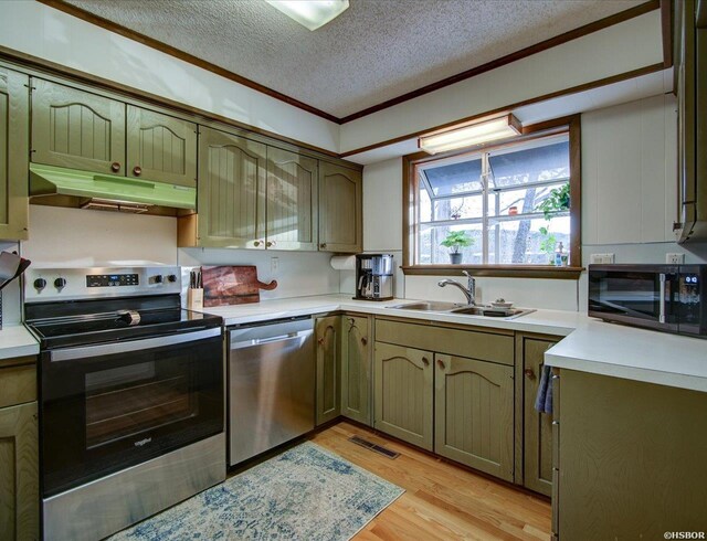 kitchen featuring stainless steel appliances, light countertops, a sink, light wood-type flooring, and under cabinet range hood