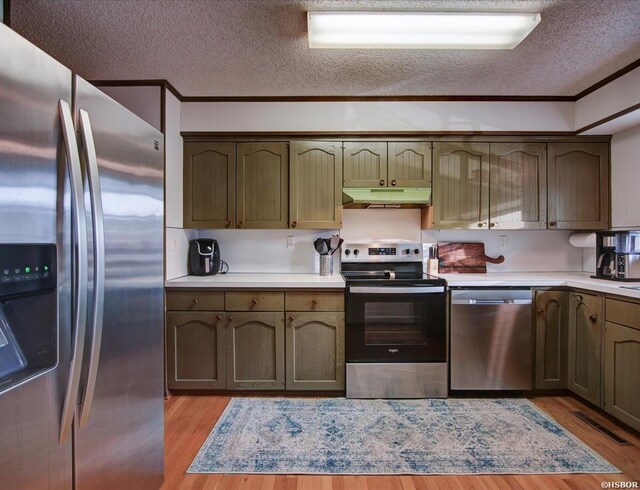 kitchen featuring stainless steel appliances, ornamental molding, light countertops, and under cabinet range hood