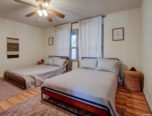 bedroom with ceiling fan, a textured ceiling, and wood finished floors