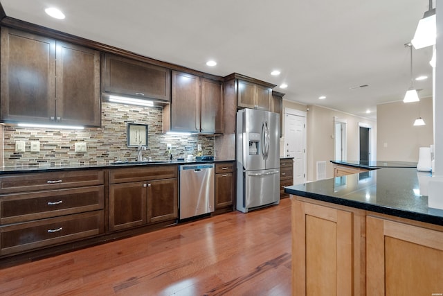 kitchen featuring a sink, wood finished floors, visible vents, appliances with stainless steel finishes, and decorative backsplash