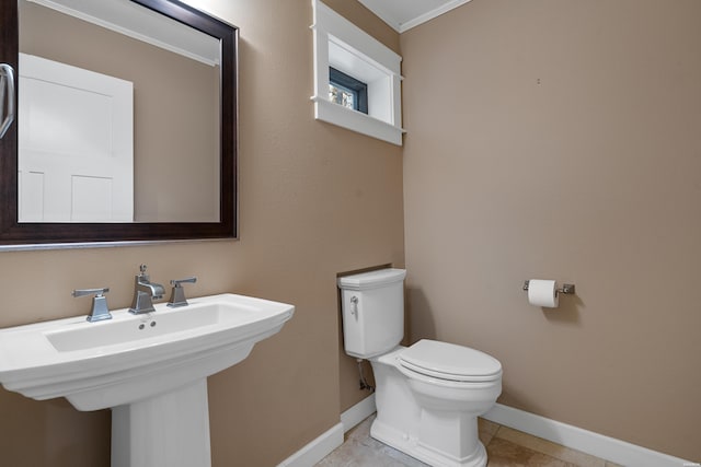 half bathroom featuring baseboards, a sink, toilet, and tile patterned floors