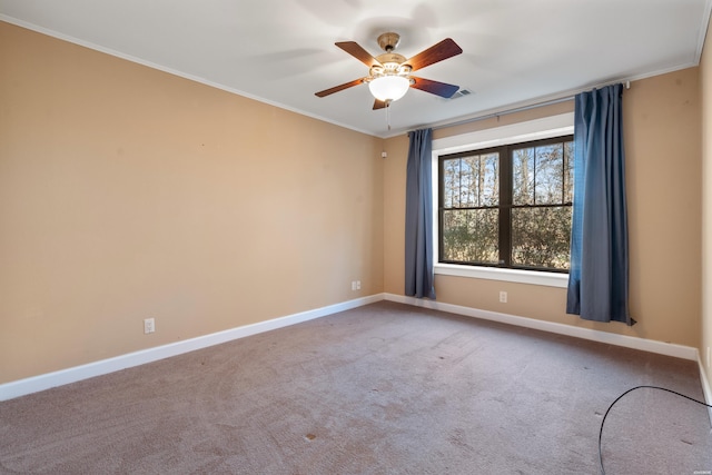 carpeted spare room with ornamental molding, visible vents, ceiling fan, and baseboards