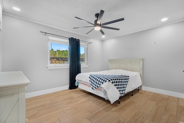 bedroom featuring a textured ceiling, light wood finished floors, and baseboards