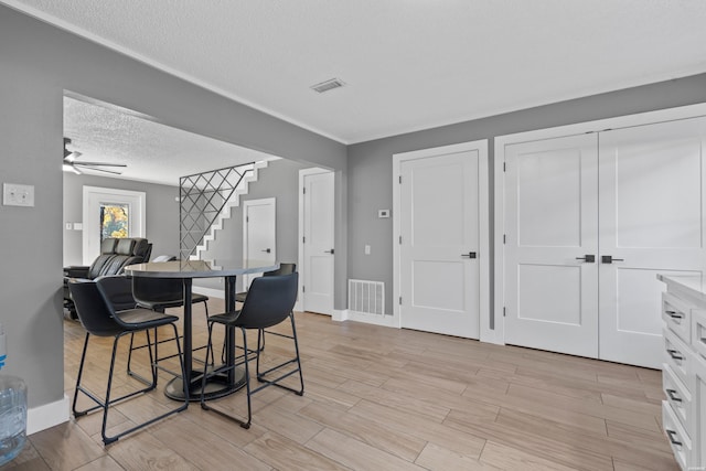 dining area featuring visible vents, wood tiled floor, stairway, and a textured ceiling