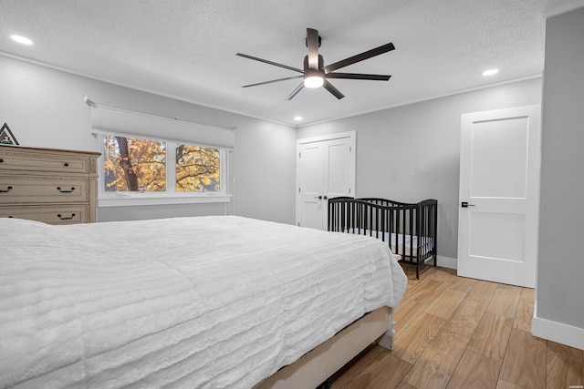 bedroom with light wood-style flooring, baseboards, a textured ceiling, and recessed lighting