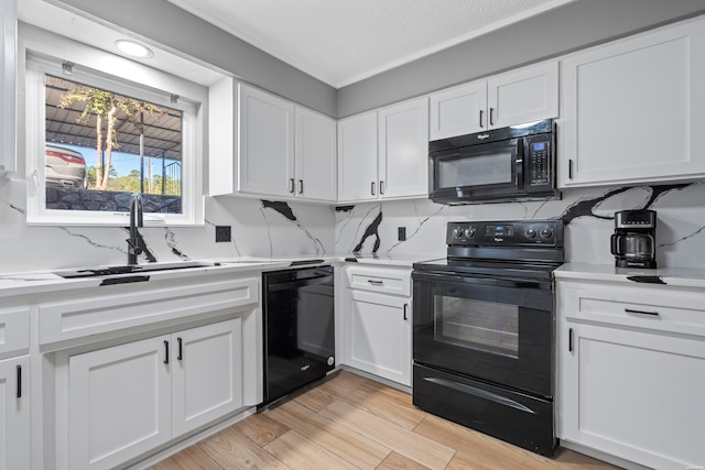 kitchen with a sink, white cabinetry, light wood-style floors, light countertops, and black appliances