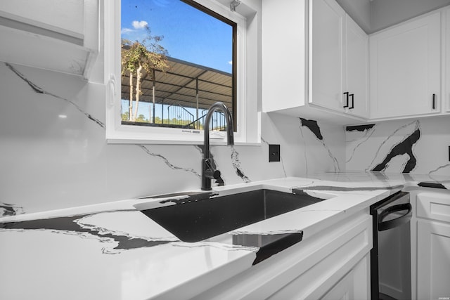 kitchen with backsplash, a sink, white cabinetry, and light stone countertops