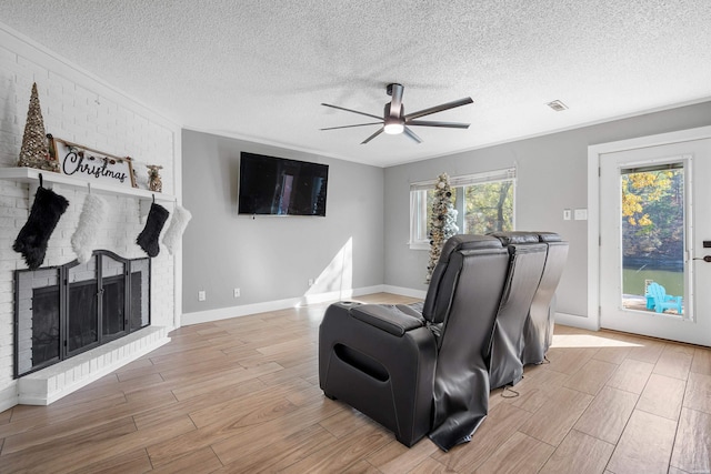 living area with light wood-type flooring, a fireplace, visible vents, and a ceiling fan