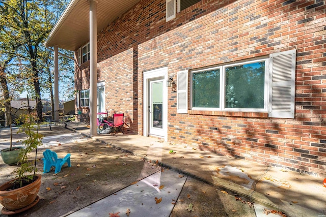 exterior space with brick siding and a patio area