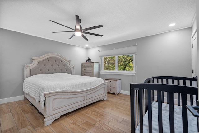 bedroom featuring a ceiling fan, baseboards, a textured ceiling, and light wood finished floors