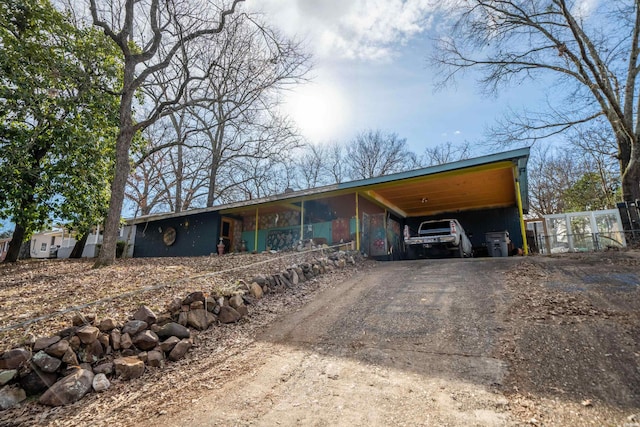 view of front of home with dirt driveway and a carport