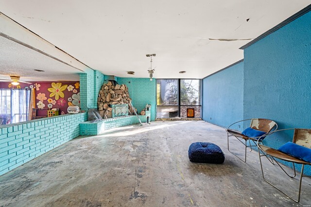 interior space featuring concrete flooring, a textured wall, and brick wall