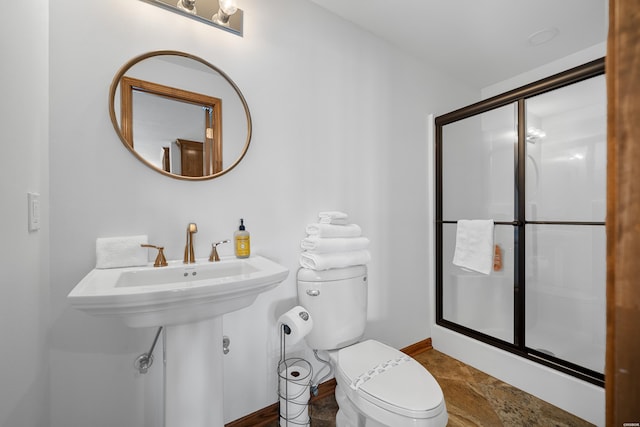 bathroom featuring toilet, a shower stall, and baseboards